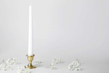 Candle with stylish holder and flowers on gray backgroundの写真素材