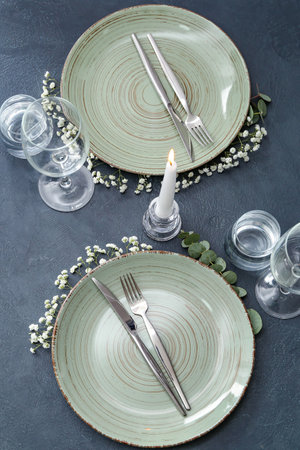 Beautiful table setting with candle and floral decor on gray background