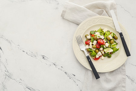 Plate with fresh Greek salad on light background