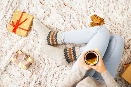 Woman in warm socks drinking tea at homeの写真素材