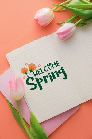 Notebook with text WELCOME SPRING and tulip flowers on pink backgroundの写真素材