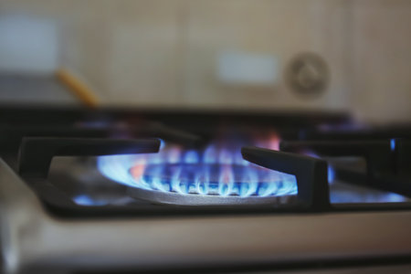 Gas burner with blue flame on domestic stove, closeup