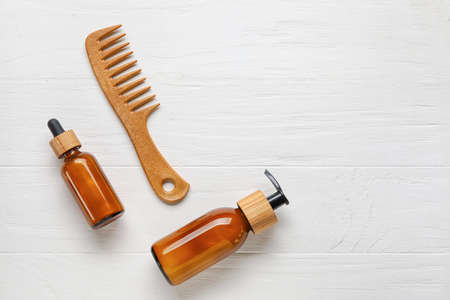 Hair comb with cosmetic serum on white wooden backgroundの写真素材