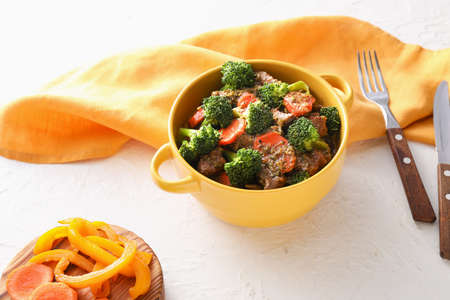 Bowl with tasty beef and vegetables on light backgroundの写真素材