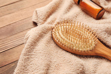 Hair brush with towel on wooden background