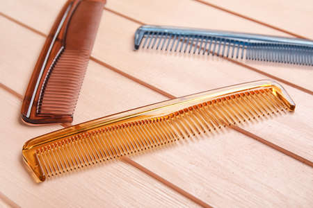 Plastic hair combs on color wooden background