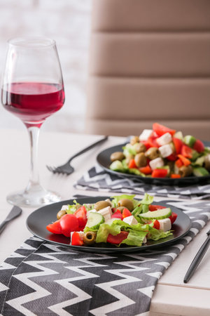Plates with fresh Greek salad on table in restaurantの写真素材