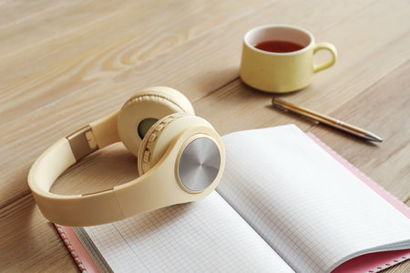 Modern headphones, cup of coffee and notebook on wooden table, closeupの写真素材