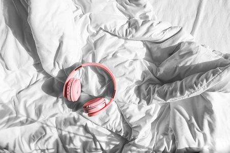 Modern headphones on bed in roomの写真素材