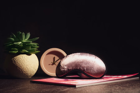 Stylish sleeping mask and magazine on dark backgroundの写真素材