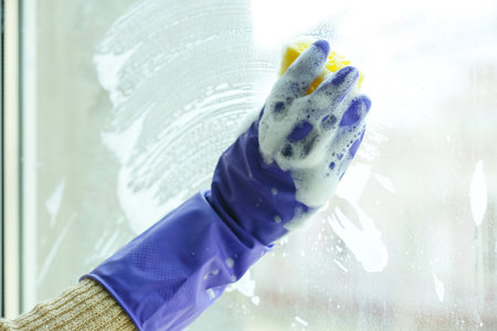 Woman cleaning window in room, closeup