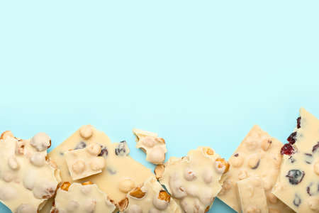 Delicious chocolate pieces with nuts on color backgroundの写真素材