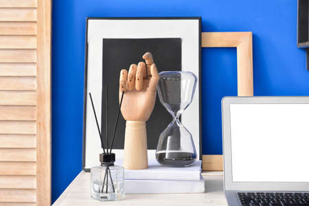Wooden hand with books and hourglass on table in room