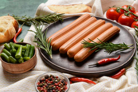 Plate with tasty sausages, vegetables and herbs on table, closeupの写真素材