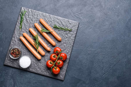 Slate plate with tasty sausages, spices and tomatoes on dark backgroundの写真素材