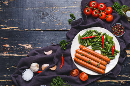 Composition with tasty sausages and vegetables on dark wooden backgroundの写真素材