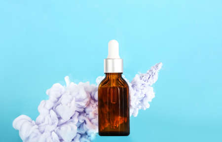 Bottle of cosmetic product in smoke on color backgroundの写真素材