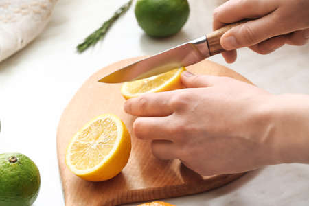 Woman cutting lemon on light backgroundの写真素材