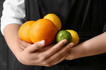 Woman with fresh citrus fruits on dark backgroundの写真素材