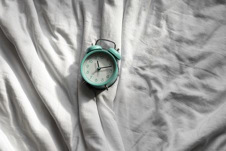 Stylish alarm clock on bedの写真素材