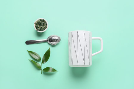 Composition with cup, dry tea and green leaves on color backgroundの写真素材