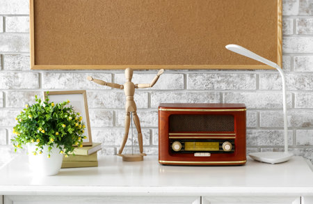 Retro radio receiver with mannequin and houseplant on table near brick wallの写真素材