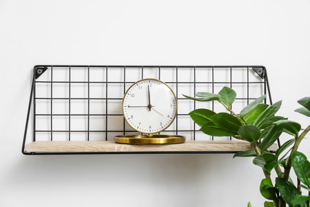 Shelf with alarm clock hanging on light wallの写真素材