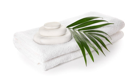 Clean towels, spa stones and palm leaf on white backgroundの写真素材