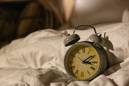 Alarm clock on bed at night, closeup