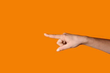 woman pointing at something on color backgroundの写真素材