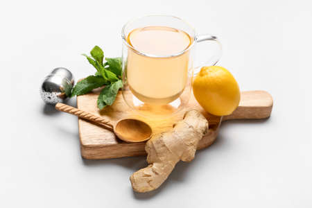 Cup of tea with ginger, mint and lemon on light backgroundの写真素材