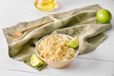Bowl with tasty couscous and lime on light wooden backgroundの写真素材