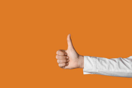 Woman showing thumb-up on color backgroundの写真素材