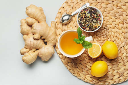 Cup of tea with ginger, mint and lemons on light backgroundの写真素材