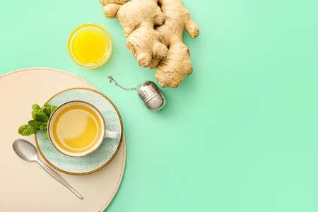 Cup of tea with ginger, mint and honey on color backgroundの写真素材