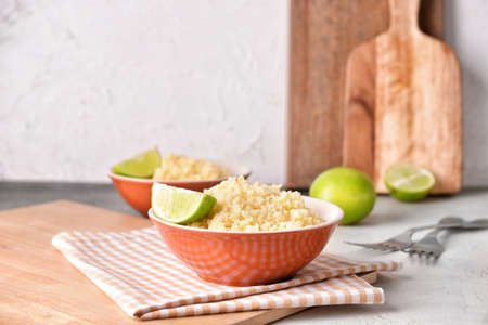 Bowls with tasty couscous and lime on tableの写真素材