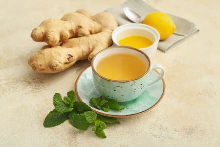 Cup of tea with ginger, honey and lemon on light backgroundの写真素材