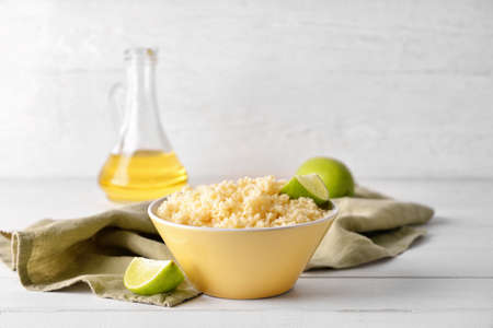 Bowl with tasty couscous and lime on light wooden backgroundの写真素材