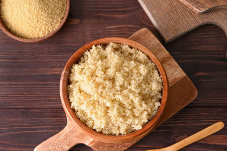 Bowl with tasty couscous on wooden background