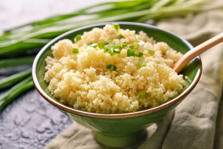 Bowl with tasty couscous and green onion on table, closeupの写真素材