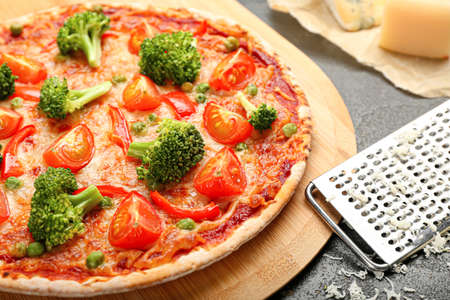 Board with tasty vegetarian pizza and grater on dark background, closeupの写真素材