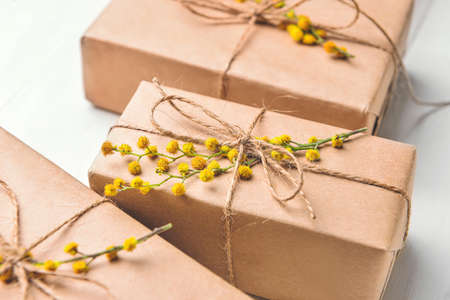 Gift boxes with mimosa branches on light wooden background, closeupの写真素材