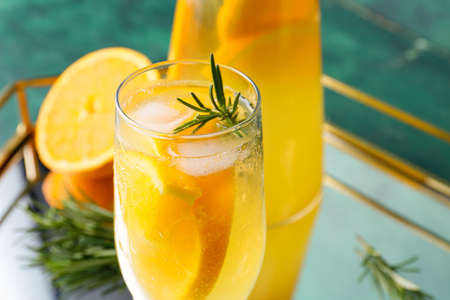Glass of tasty orange cocktail with rosemary on color background, closeupの写真素材