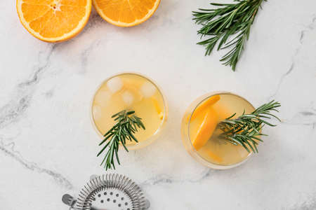 Glasses of tasty orange cocktail with rosemary on light backgroundの写真素材