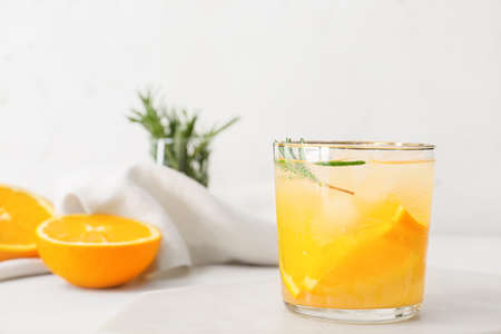Glass of tasty orange cocktail with rosemary on light backgroundの写真素材