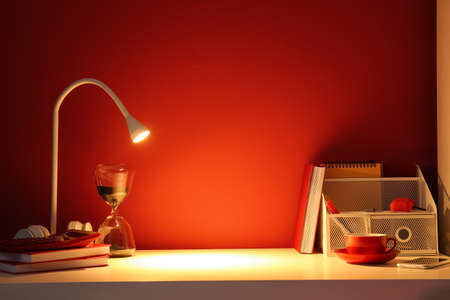Modern workplace with glowing lamp near color wallの写真素材