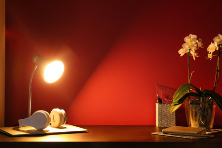 Modern workplace with glowing lamp near color wallの写真素材