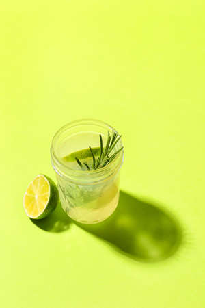 Glass of tasty lime cocktail with rosemary on color backgroundの写真素材