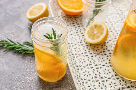 Glass of tasty orange cocktail with rosemary on gray background, closeupの写真素材