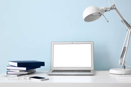 Modern workplace with laptop near color wallの写真素材